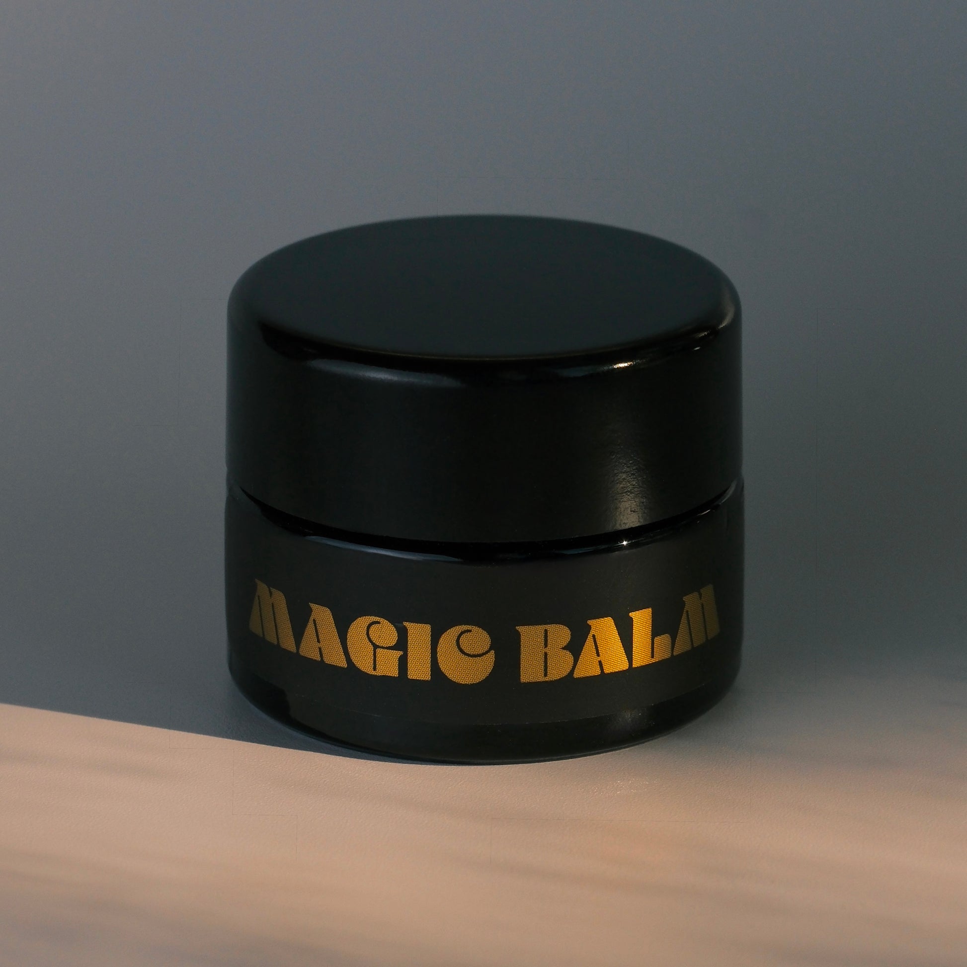 Black jar of Magic Balm nose balm for inside nose photographed against a neutral background