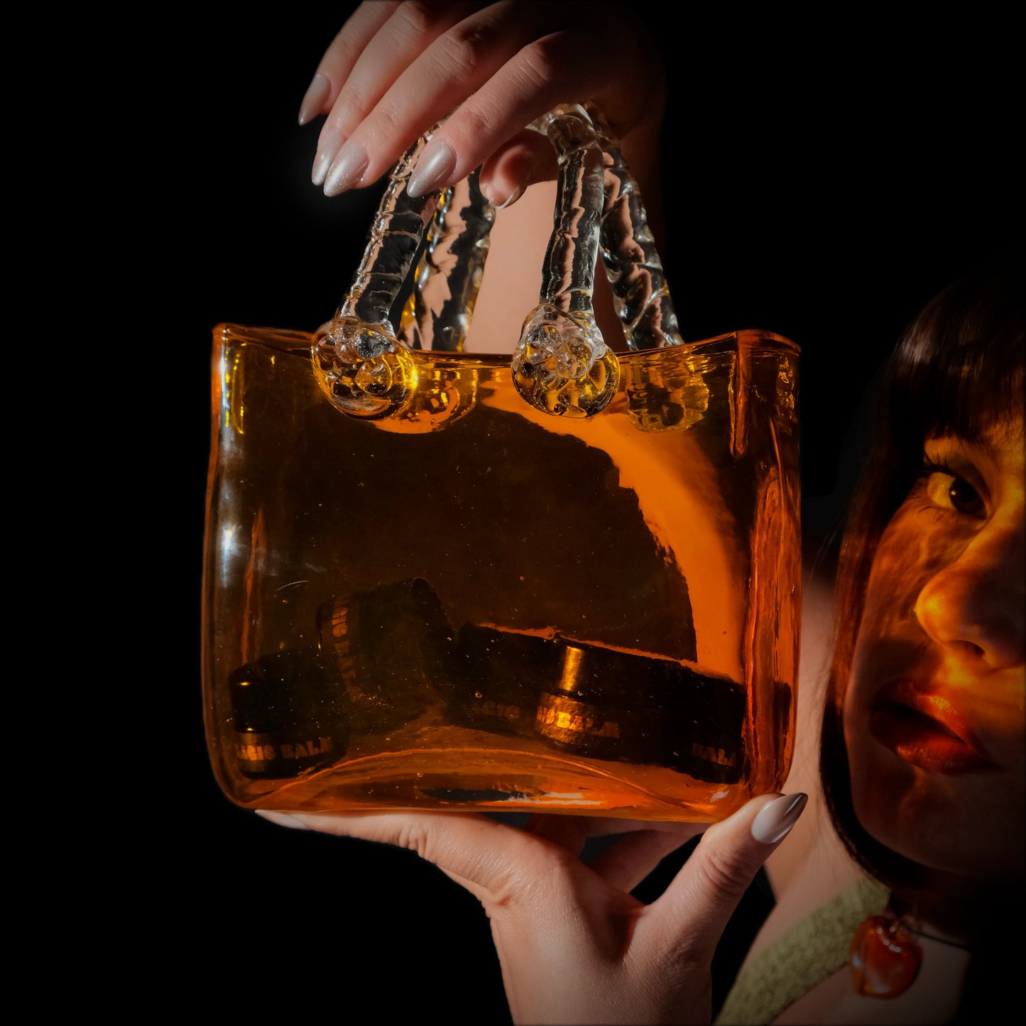 Model holding a transparent amber bag containing Magic Balm nasal balm jars